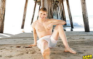 Sexy Keiran poses on a beach before going inside and revealing his big cock