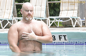 Burly bald bear Brick Hampton takes a dip in the pool naked and massages his cock
